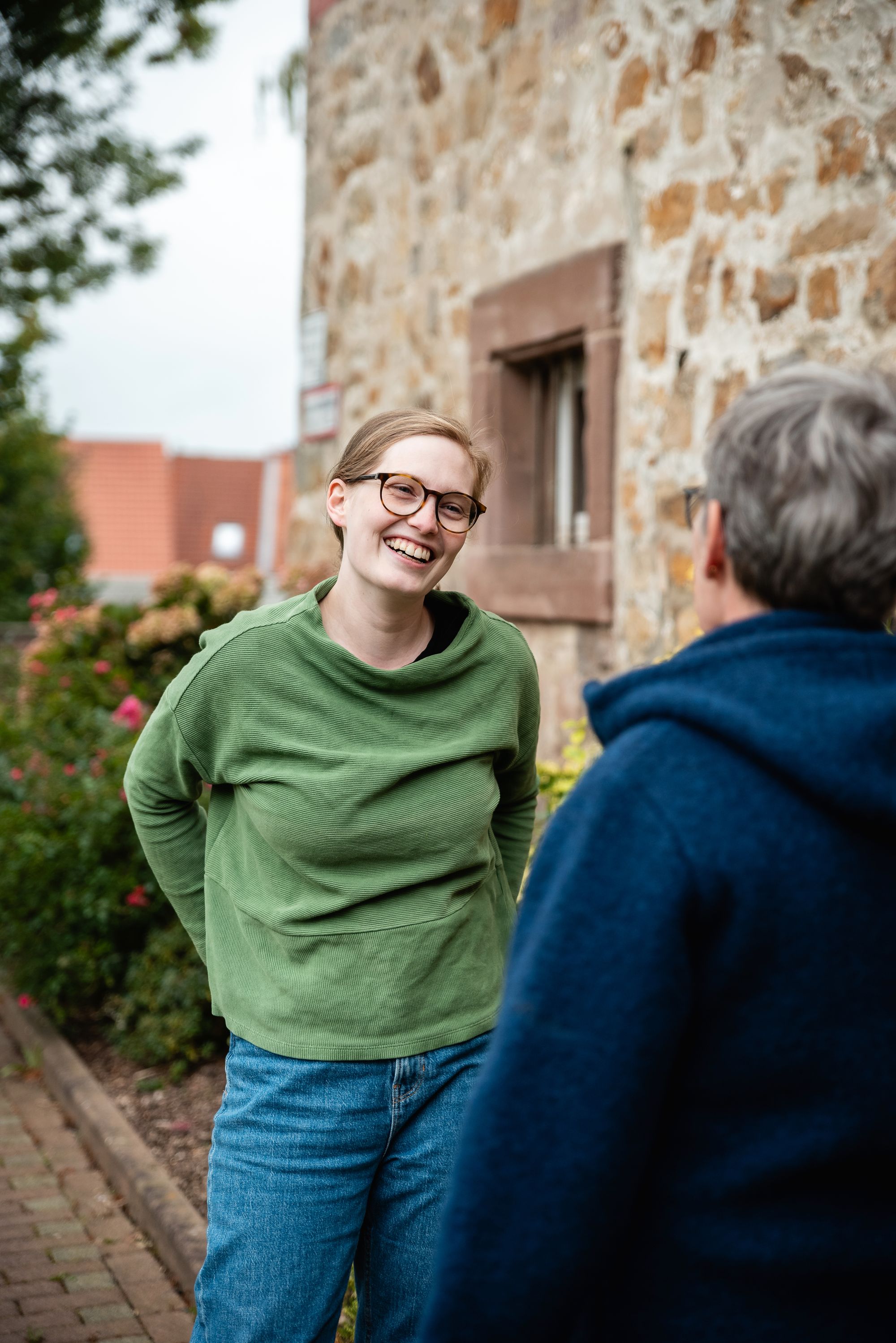 Karoline Otte im Gespräch mit einer Bürgerin vor einem Haus im rustikalen Stil.